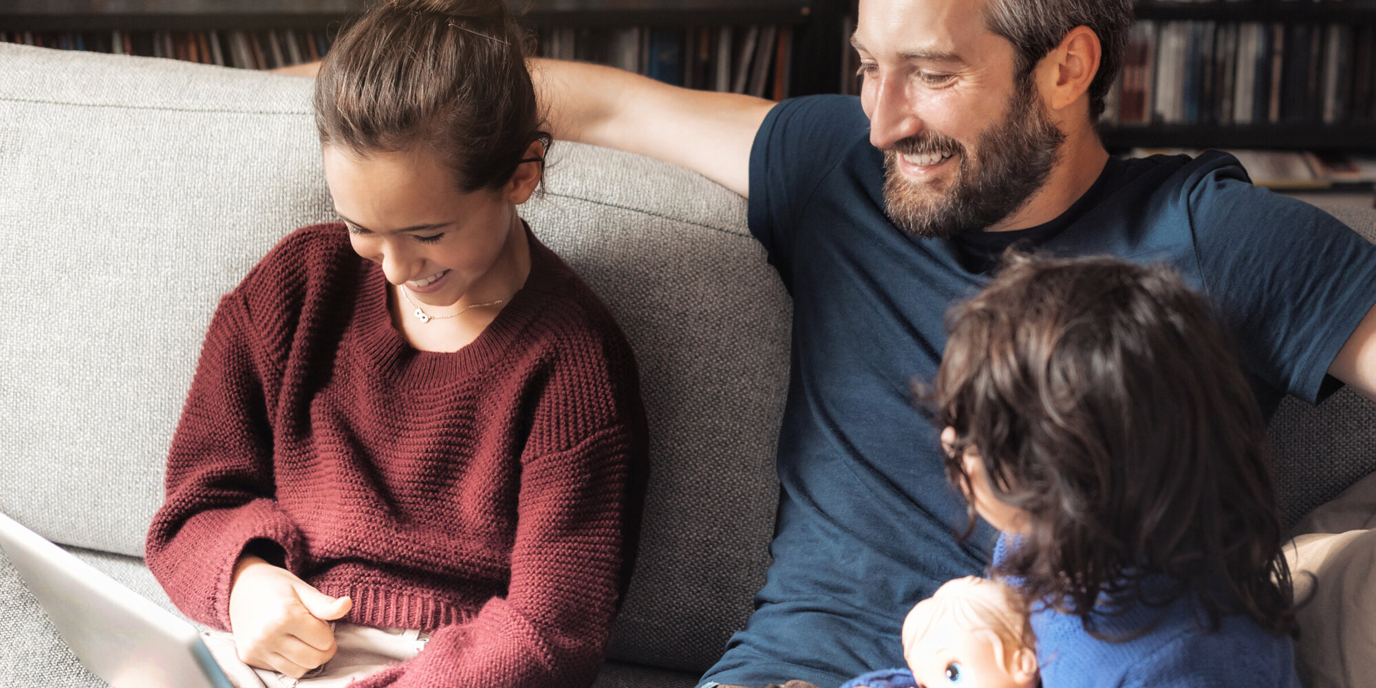 Vater schaut mit seinen kleinen Kindern in ein Laptop